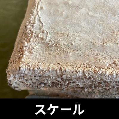 長年のスケールがこびりついた御影石