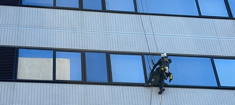 ロープアクセスによる高所窓ガラス清掃の様子。