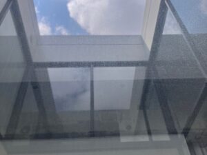 高所ガラスに固着した水垢とスケール汚れの施工前状態