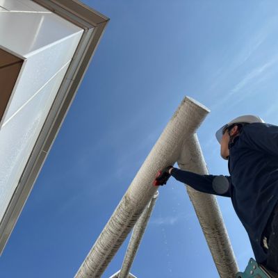 ロープ作業で高所の窓ガラスを清掃中。安全帯を着用し、ビルの外壁を丁寧に洗浄している様子