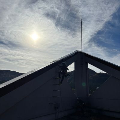 高所窓の汚れをブラシで落とす作業員。オフィスビル外壁の黒ずみや水垢を除去している場面。