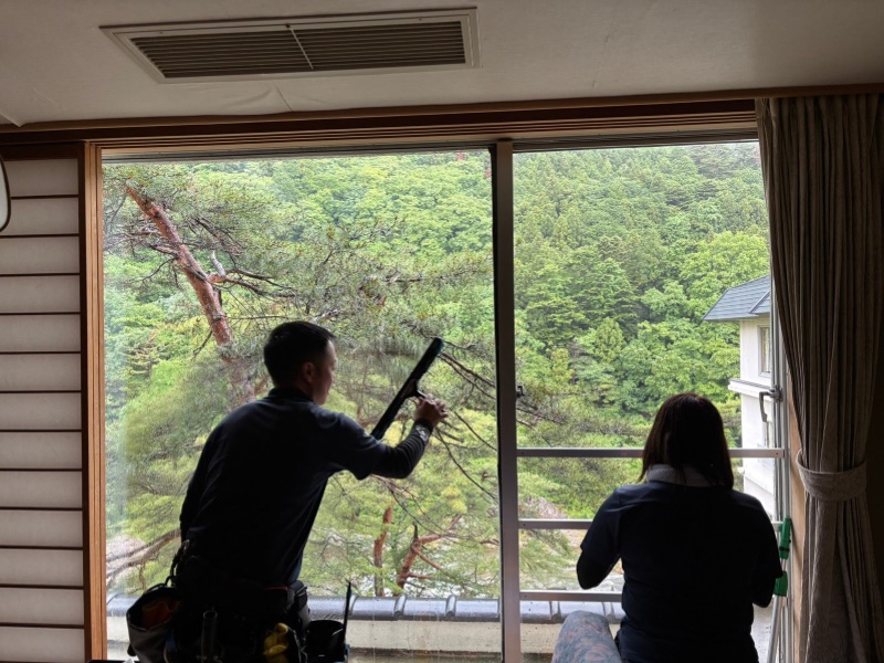 旅館の窓ガラスを専用道具で清掃している作業風景