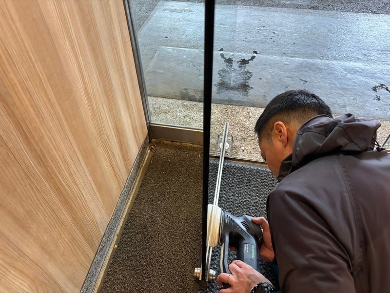 旅館ロビー入り口のガラス焼けを研磨で除去する様子