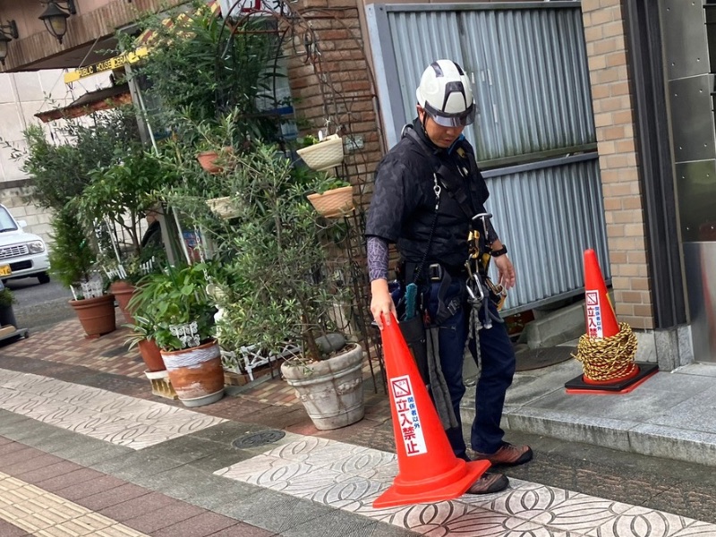 前橋市のオフィスビルで高所ガラス清掃前にカラーコーンを設置する様子