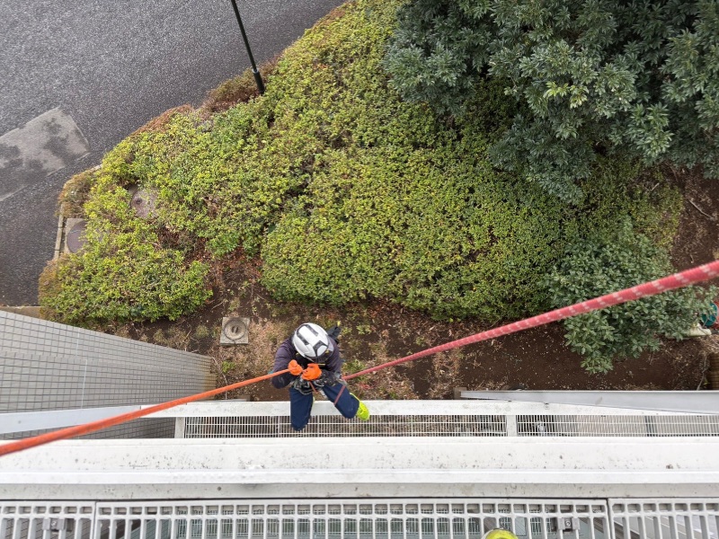 ブランコ工法で下降しながら清掃を行う作業員。足場不要で道路使用許可のリスクも最小限に抑制。