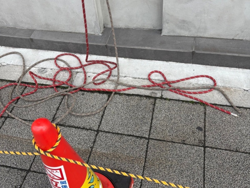 ビル地上階の歩行者誘導と立ち入り禁止措置。カラーコーンと監視員による安全確保。