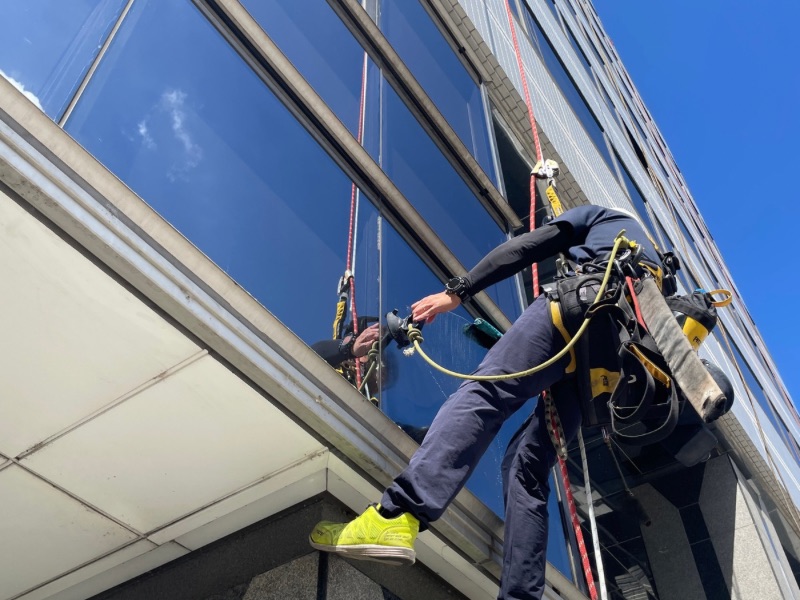 高崎市の13階建てオフィスビルでロープアクセスによる窓ガラス清掃を行う作業員
