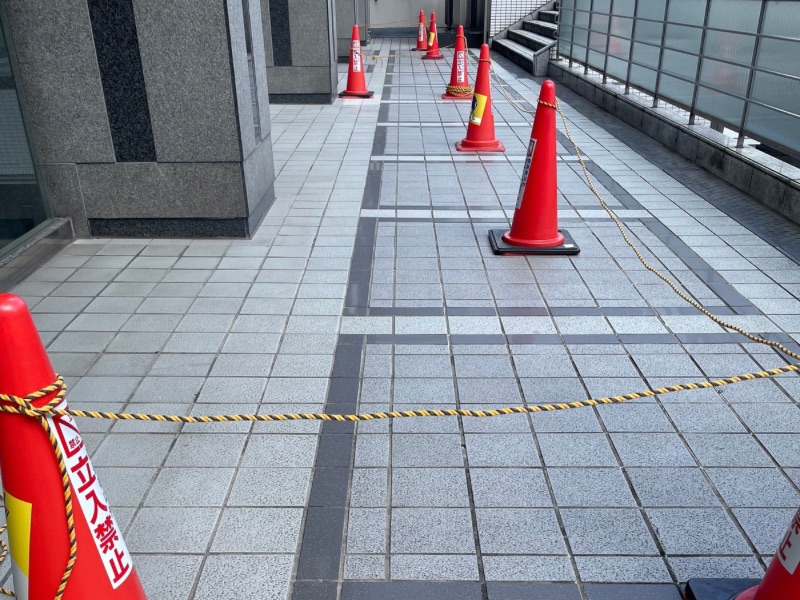 高所窓ガラス清掃時にカラーコーンで作業エリアを立入制限している様子